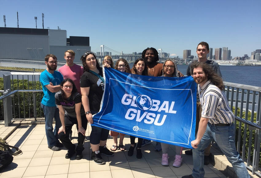 Students holding a global gvsu flag in Japan